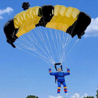 RC skydiver in the air with a black and yellow parachute.