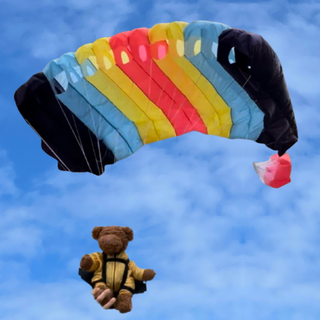 Teddy bear flying with a multicolor mini parachute.