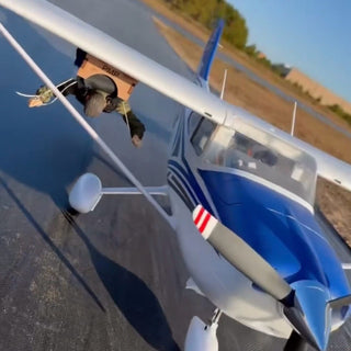 Parachute dropping system under cessna rc plane on runway.