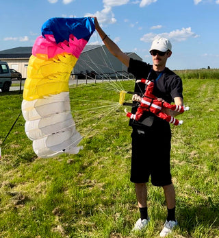 RC parachute held by a pilot in a field.