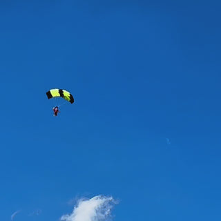 Radio controlled parachutist landing in a field.