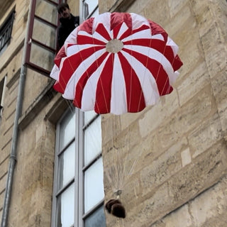 Red and white round toy parachute falling.