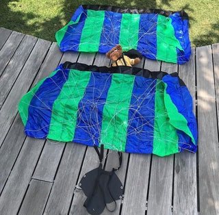 Two green and blue mini parachutes laying down in a garden.